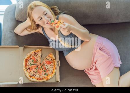 Eine schwangere Frau genießt ein Stück Pizza und genießt einen Moment der Genussfreude, während sie ihr Verlangen nach einer köstlichen, wohltuenden Leckerei befriedigt. Begeistert Stockfoto