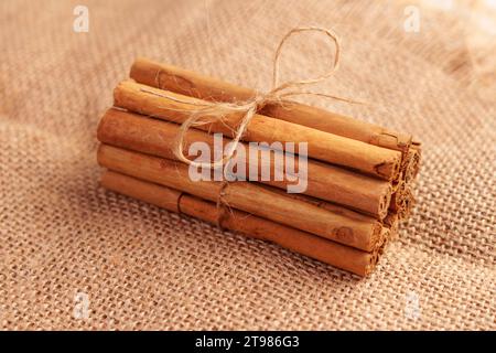 Getrocknete Zimtstäbchen, die mit einem Garnseil auf einem Sackleinen gebunden sind. Weihnachtskost und Aromatherapiekonzept Stockfoto