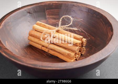 Ein Haufen gebundener Zimtstangen mit Garn in einer rustikalen Holzschale. Rohes aromatisches Gewürz. Weihnachtszutat. Gesunde Ernährung. Stockfoto