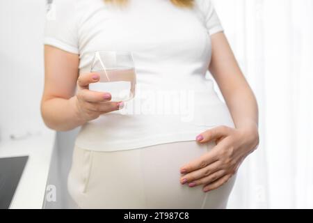 Nahaufnahme eines Wasserglases in der Hand der schwangeren Frau. Diät in der Schwangerschaft. Stockfoto