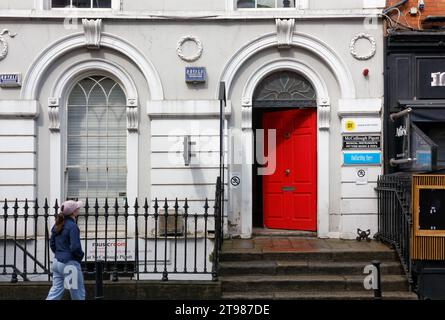 DUBLIN, Irland - 5. August 2023: Öffnen Sie die rote Tür eines historischen Gebäudes an einer Stadtstraße Stockfoto