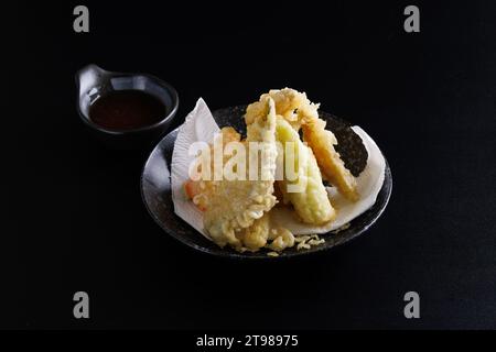 Mischen Sie Tempura mit Garnelenfisch und japanischem Gemüse, isoliert auf schwarzem Hintergrund Stockfoto