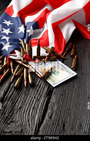 Amerikanische Flagge, Dollar, Kugeln, Patronen, Munition auf schwarzem hölzernem Hintergrund. Das Konzept des Leihpachtvertrags, der Armee, des Waffenverkaufs. Militär Stockfoto