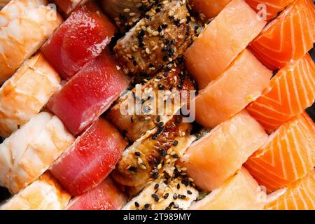 Ein großes Set Sushi-Brötchen mit Garnelen, Lachs, Thunfisch, Aal, Draufsicht, Nahaufnahme. Sushi-Lieferung. Rollt als Hintergrund. Stockfoto