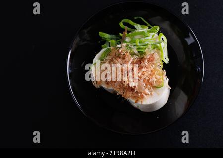 Japanischer Tofu Japanische Vorspeise weicher kalter Tofu mit Ingwersauce und grüner Zwiebelauflage isoliert auf schwarzem Hintergrund Stockfoto