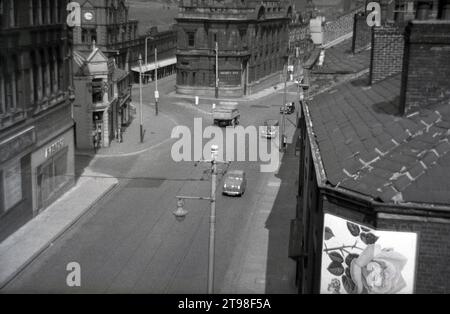 1950er Jahre, historischer Blick von oben auf eine Kopfsteinpflasterstraße in Oldham Town, Nordengland, mit einer Zweigstelle der District Bank. Das 1906 eröffnete markante Gebäude wurde von den Architekten Mills & Murgatroyd in einem barocken Architekturstil entworfen. Ursprünglich 1829 als Manchester and Liverpool District Bank gegründet, wurde ihr Name 1924 in District Bank verkürzt. 1962 wurde sie von der National Provincial Bank übernommen, blieb aber bis zu ihrer Fusion mit der Westminster Bank im Jahr 1968 als separate Bank bestehen. Stockfoto