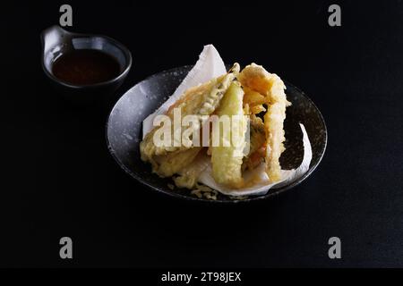 Mischen Sie Tempura mit Garnelenfisch und japanischem Gemüse, isoliert auf schwarzem Hintergrund Stockfoto