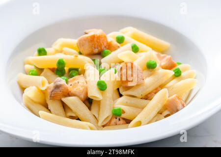 Pasta Penne mit Lachs und grünen Erbsen Stockfoto