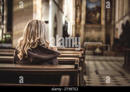 Die christliche Frau betet in der Kirche. Religion und Spiritualität. Schweigendes Gebet zu Gott Stockfoto