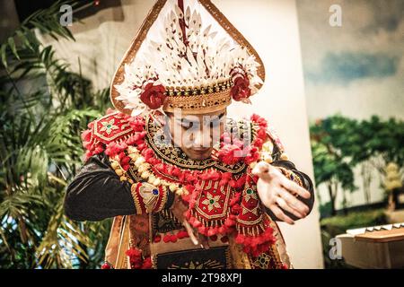 Ein männlicher balinesischer Tänzer tanzt einen traditionellen balinesischen Tanz in traditioneller balinesischer roter Kleidung in einem Café in Shanghai, China Stockfoto