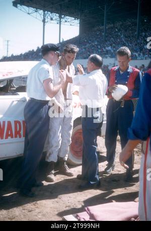 SACRAMENTO, KALIFORNIEN - AUGUST 1958: Eine Gruppe von Männern kümmert sich um den Fahrer, nachdem sein Auto während einer Autoausstellung auf der Sacramento State Fair um den August 1958 in Sacramento, Kalifornien, umgekippt und abgestürzt ist. (Foto: Hy Peskin) Stockfoto