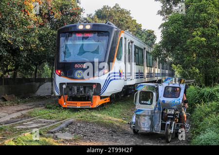 Manila, Philippinen. 24. November 2023 : Ein Dreirad fährt in der Nähe eines Dieseltriebs der Klasse PNR 8000 (hergestellt in Indonesien), der als Interprovincial Pendler von den Philippine National Railways (PNR) betrieben wird, die heute ihr 131-jähriges Bestehen feiern. Die Philippinen führen derzeit einen ehrgeizigen Eisenbahnausbau durch, bei dem ab Januar 2024 der Betrieb in der National Capital Region (Metro Manila) für fünf Jahre eingestellt wird, von dem täglich etwa 30.000 Filipinos betroffen sein werden, um dem Bau des North-South Commuter Railway (NSCR)-Projekts Platz zu geben. Quelle: Kevin Izorce/Alamy Live News Stockfoto