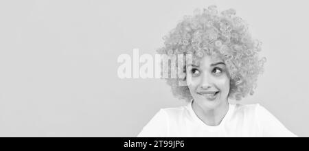 Verträumte freaky Frau in lockigen Clown Perücke Stellen Sie sich etwas vor, Phantasie. Frau isoliert Gesicht Porträt, Banner mit Kopieplatz. Stockfoto