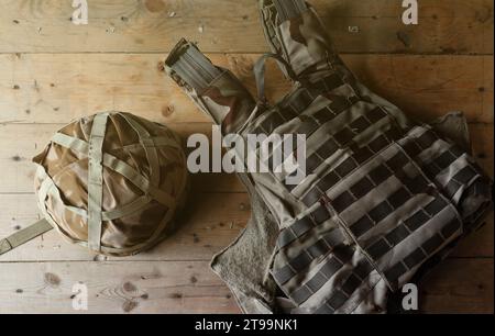 Ein Militärhelm eines ukrainischen Soldaten mit einer schweren kugelsicheren Weste auf einem Holztisch im Innenraum des Kontrollpunktes Stockfoto