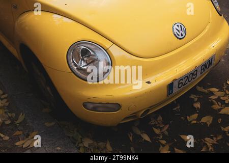 Madrid, Spanien 22. November 2023 Volkswagen New Beetle. Kompaktes, hellgelbes Auto. Draufsicht auf die Stoßstange und die Scheinwerfer auf der herbstlichen Stadtstraße Stockfoto