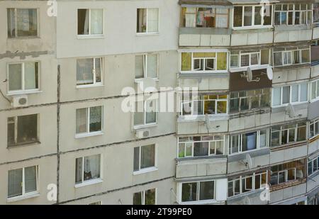 Fassade eines grauen mehrstöckigen sowjetischen Paneelgebäudes. Russische alte urbane Wohnhäuser mit Fenstern und Balkon. Typische russische Nachbarschaft Stockfoto