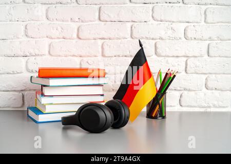 Stapel Bücher und Flagge Deutschlands auf dem Schreibtisch. Deutschsprachenlernkonzept Stockfoto