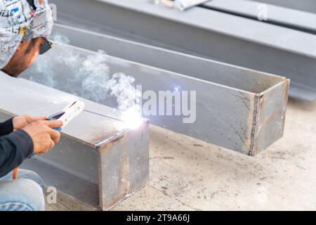 Schweißer schweißt i-Träger für Stahlkonstruktionsarbeiten mit dem Prozess Flux Cored Arc Welding (FCAW) in einer industriellen Fabrik. Stockfoto