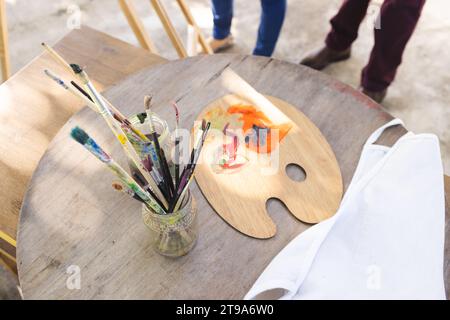 Nahaufnahme von Farben und Gläsern mit Pinseln auf Holztisch auf der sonnigen Terrasse. Lebensstil, Ruhestand, Seniorenleben, Kreativität und häusliches Leben, una Stockfoto