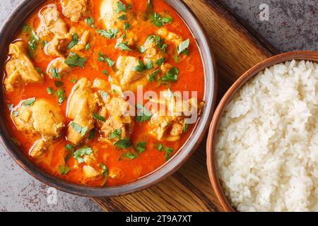 Leckeres Lahori Hühnchen Karahi serviert mit Reis Nahaufnahme auf dem Holzbrett auf dem Tisch. Horizontale Draufsicht von oben Stockfoto