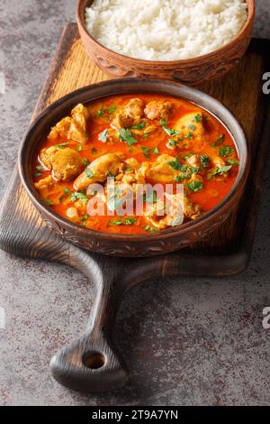 Lahori Chicken ein indisches Hühnchen-Curry-Gericht aus Pakistan, serviert über Basmati-Reis-Nahaufnahme auf dem Holzbrett auf dem Tisch. Vertikal Stockfoto