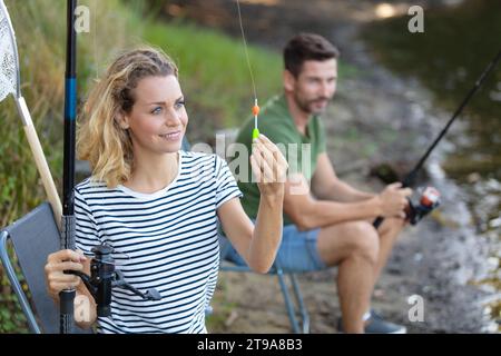 Ein Paar fischen zusammen in der Nähe des Flusses mit einer Angelrute Stockfoto