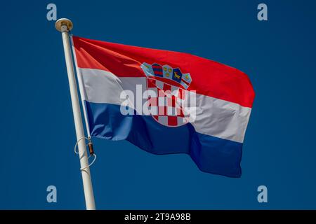 Kroatien-Flagge winkt gegen den klaren blauen Himmel, isoliert in rot-weiß-blauen Farben Stockfoto