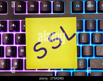 SSL, Sicherheitszertifikat auf einem gelben Aufkleber auf einer Laptop-Tastatur mit Hintergrundbeleuchtung. Stockfoto