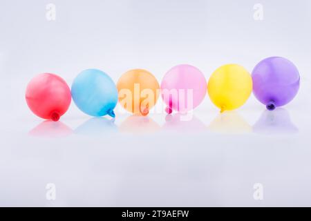 Bunte kleine Luftballons in Linie auf weißem Hintergrund Stockfoto