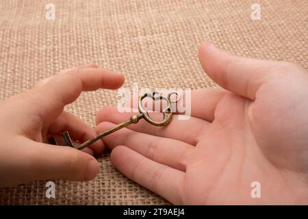 Hand mit einem goldenen Schmuckschlüssel im Retro-Stil Stockfoto