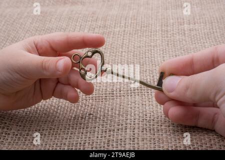 Hand mit einem goldenen Schmuckschlüssel im Retro-Stil Stockfoto