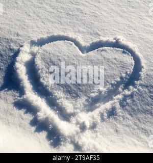 Eine Nahaufnahme einer Herzform aus frisch gefallenem Schnee in einer winterlichen Landschaft Stockfoto