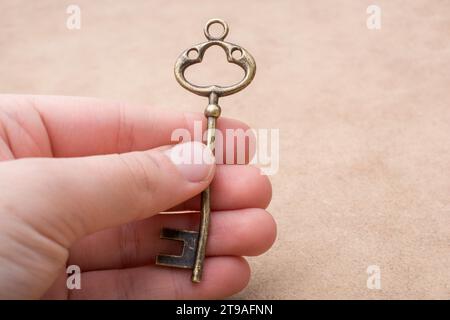 Hand mit einem goldenen Schmuckschlüssel im Retro-Stil Stockfoto