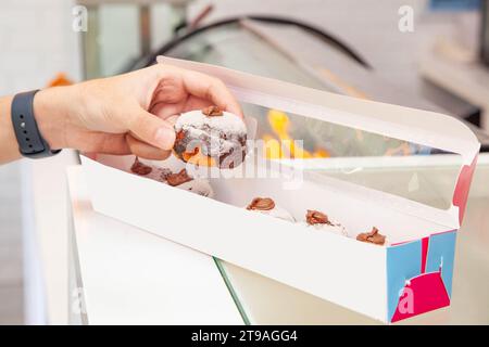 Mini-Donuts mit Schokoladenfüllung, die aus einer Schachtel pflücken. Stockfoto