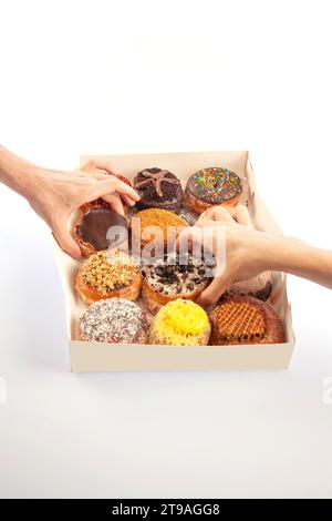 Schachtel mit zwölf großen Donuts, gemischt Brioche und schick mit Händen. Stockfoto