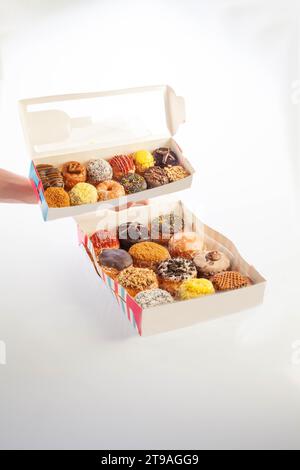 Schachtel mit zwölf großen Donuts, gemischt Brioche und schick mit Händen. Stockfoto