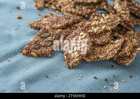 Gesundes salziges Vollkorngebäck aus Hafer und Leinsamen gebacken, belegt mit verschiedenen Samen auf einer blauen Serviette, Kopierraum, ausgewählter Fokus, schmaler Dep Stockfoto