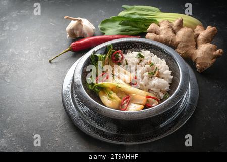 Vegetarische Mahlzeit aus Reis ad Pak Choi (Chinakohl) mit Ingwer, Knoblauch und rotem Chili in einer schwarzen Keramikschale auf dunklem Hintergrund, Kopie sp Stockfoto