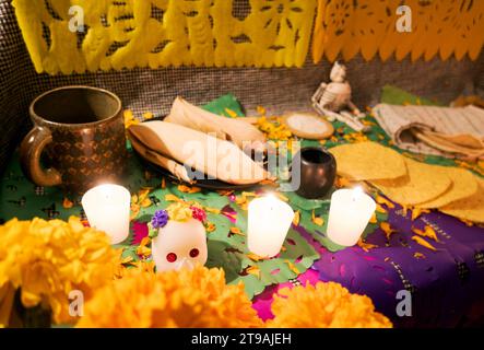 Ein Tag des toten Altars mit Schädeln, Cempasuchil-Blumen, Essen und Kerzen Stockfoto