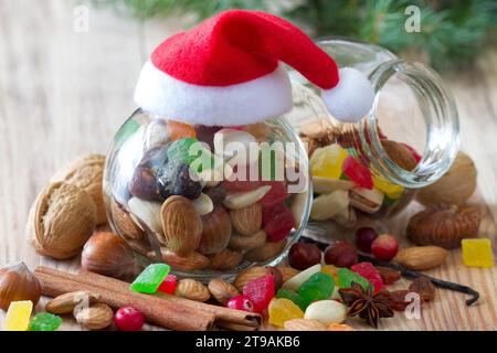 Weihnachtsmischung aus Nüssen und getrockneten Früchten im Glas mit weihnachtsmütze, weihnachtsessen-Konzept Stockfoto