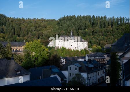 Blick auf die Gemeinde Clervaux mit Stadtstatus im Norden Luxemburgs und grünen Wald, Hauptstadt des Kantons Clervaux, weißes Schloss bei Sonnenuntergang Stockfoto