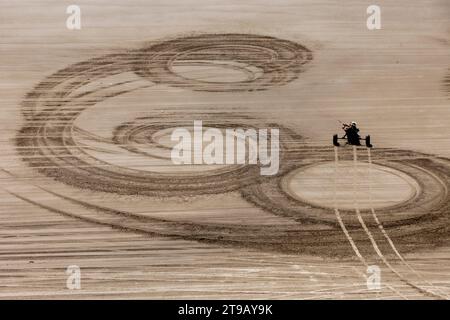 Hochwinkelperspektive eines männlichen Kite Buggers (Kite Buggy), der durch interessante Formen und Texturen im Sand an einem Strand rollt. Stockfoto