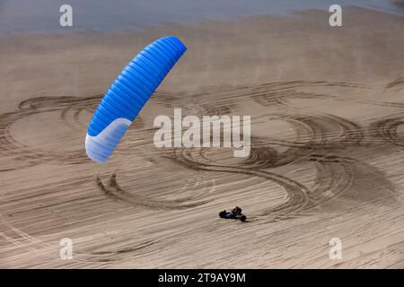 Ein Kite-Buggy rollt durch Formen und Texturen im Sand am Strand. Stockfoto