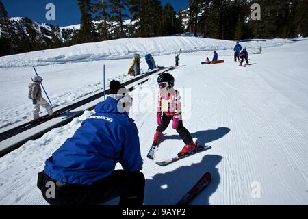 Skilehrer hilft einem jungen Skifahrer auf einer Hasenpiste. Stockfoto