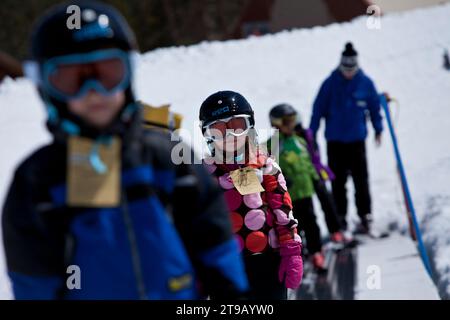 Junge Skifahrer und ihr Lehrer auf einem magischen Teppichlift. Stockfoto