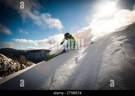 Ein männlicher Skifahrer macht eine harte Kurve in nettem Licht. Stockfoto