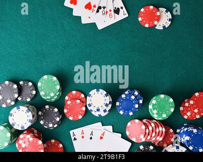 Gewinnhand mit Poker aus Assen und einem Haufen Chips auf dem Tisch an einem Ende und Verlierer ohne Spiel vorne auf grüner Matte. Draufsicht. Stockfoto