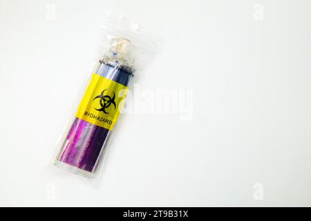 Ein entsorgter, leuchtend lila Einweg-Zigarettenvape wurde in einen kleinen Plastikbeutel mit einem hellgelben Schild für biologische Gefahrenstoffe gelegt. Stockfoto