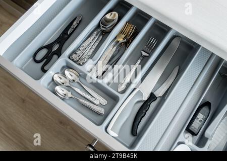 Offene Schublade mit Küchenutensilien, einschließlich Gabeln, Löffeln, Scheren und Messern Stockfoto