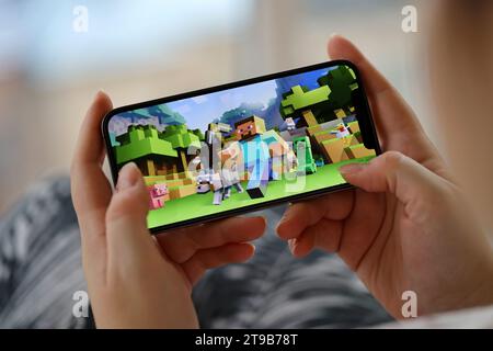 Minecraft mobiles iOS-Spiel auf dem iPhone 15 Smartphone-Bildschirm in weiblichen Händen während des mobilen Gameplays. Mobiles Gaming und Entertainment auf einem tragbaren Gerät Stockfoto